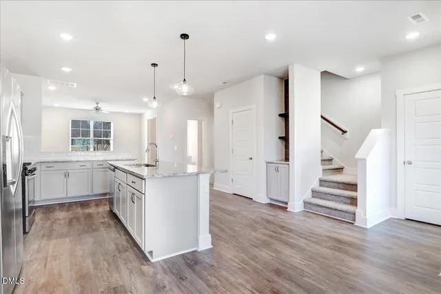 a kitchen with stainless steel appliances kitchen island wooden floors white cabinets and window