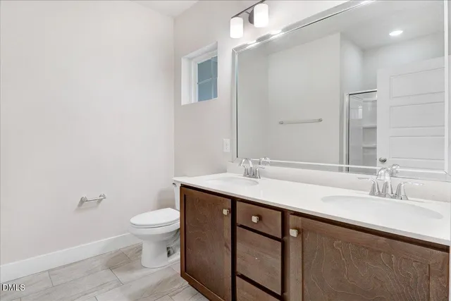 a bathroom with a sink a toilet a mirror and shower