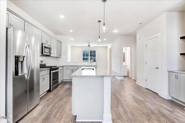 a large kitchen with a center island wooden floor stainless steel appliances and a window