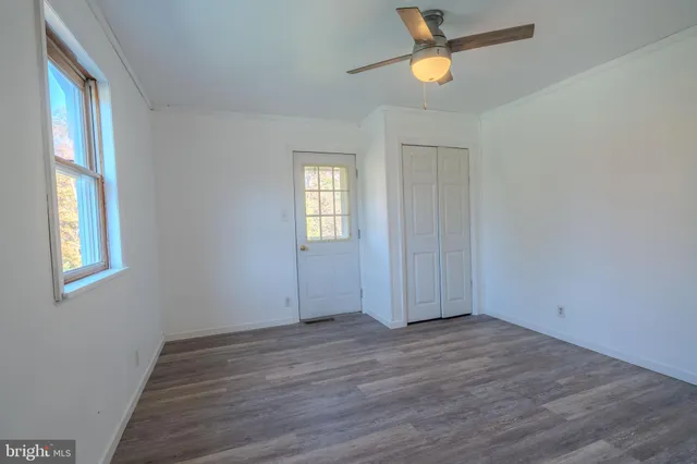 a view of empty room with wooden floor and fan