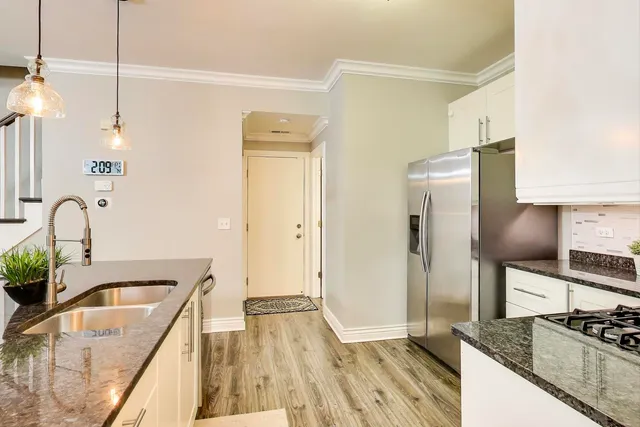 a kitchen with granite countertop a refrigerator a sink a stove and wooden floor