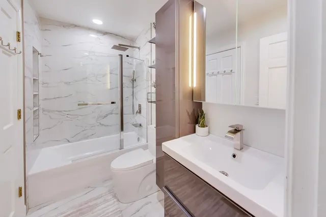 a bathroom with a bathtub shower sink mirror and toilet