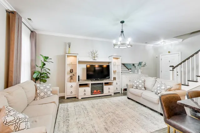 a living room with furniture a flat screen tv and a chandelier