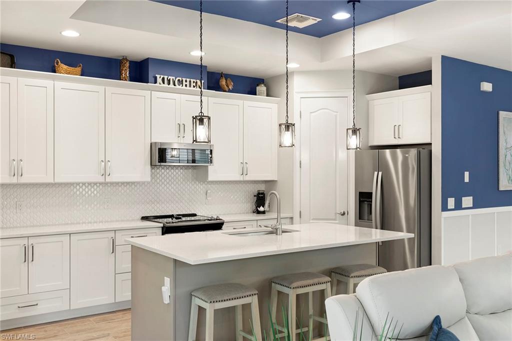 14796 Windward Lane Naples, FL 34114 - Photo 12 of 50 a kitchen with stainless steel appliances a refrigerator a sink dishwasher a stove and white cabinets with wooden floor