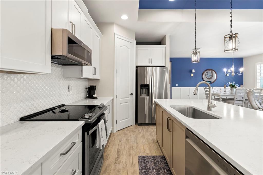 14796 Windward Lane Naples, FL 34114 - Photo 16 of 50 a kitchen with stainless steel appliances granite countertop a sink stove and refrigerator
