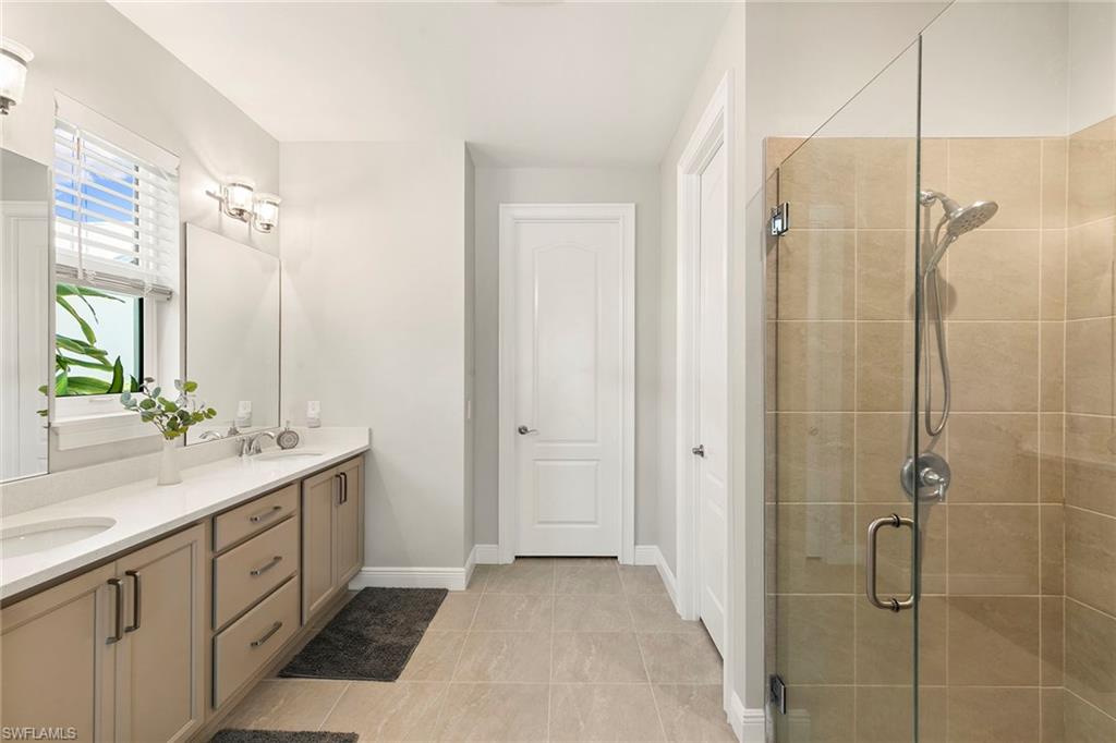 14796 Windward Lane Naples, FL 34114 - Photo 20 of 50 a bathroom with a double vanity sink a large mirror a shower and a bathtub