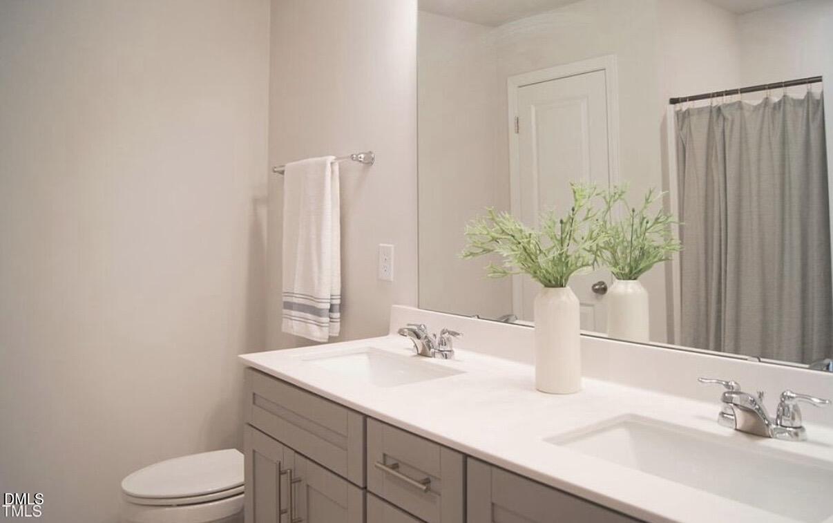 5006 Tura Street Raleigh, NC 27610 - Photo 28 of 32 a bathroom with a granite countertop sink a toilet and a mirror