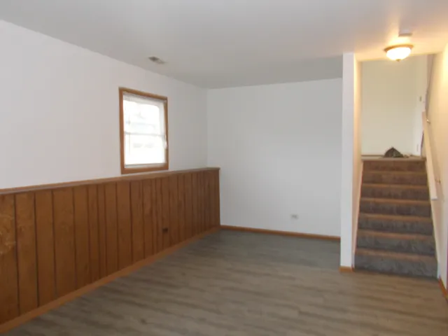 an empty room with wooden floor cabinet and windows