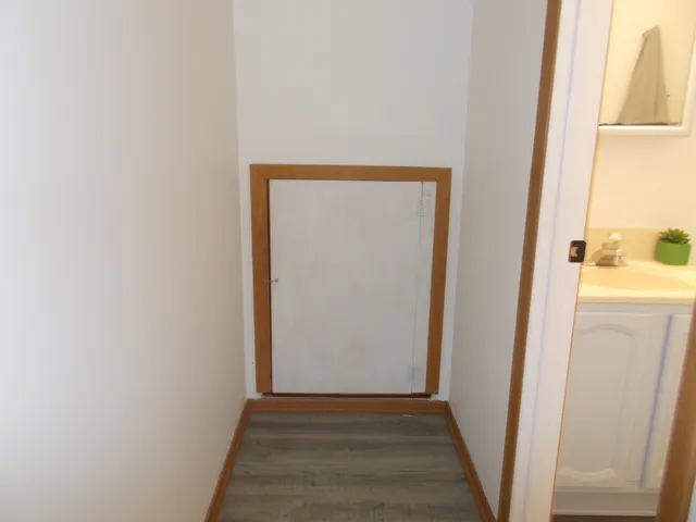a view of a hallway with wooden floor and a bathroom