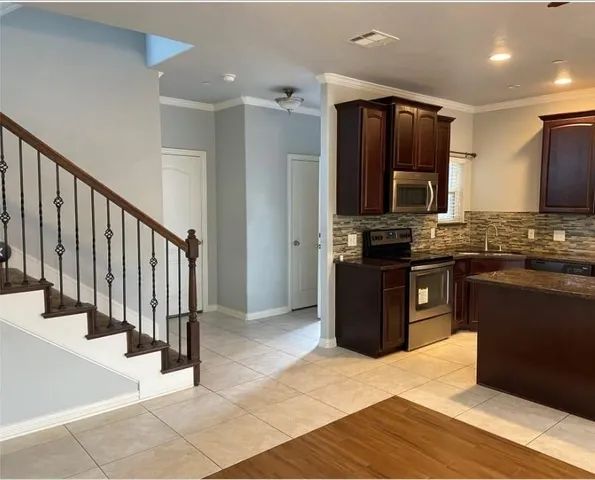 a kitchen with stainless steel appliances kitchen island granite countertop a refrigerator and a stove top oven