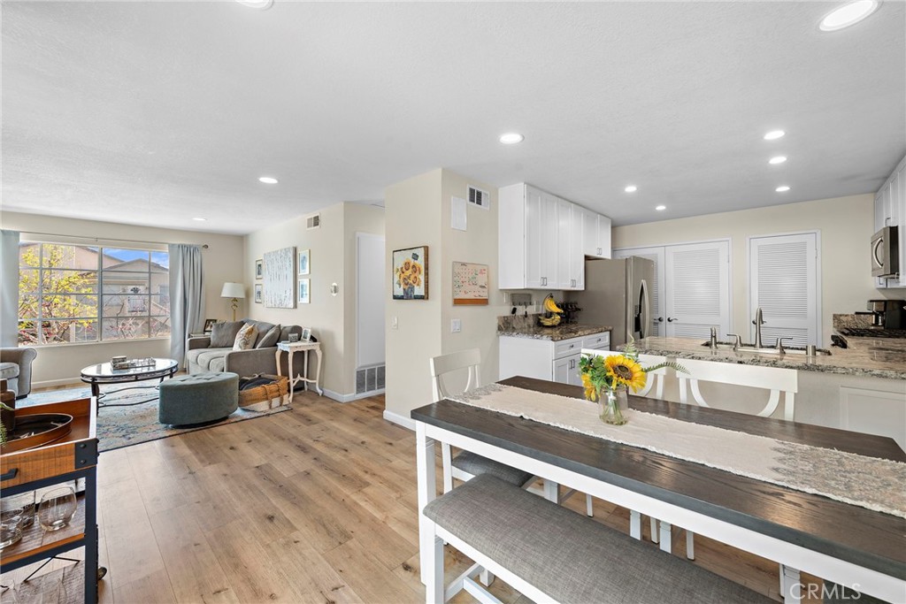 22 Exeter, Unit 23 Irvine, CA 92612 - Photo 11 of 30 a kitchen with stainless steel appliances granite countertop a refrigerator a stove top oven a dining table and chairs with wooden floor