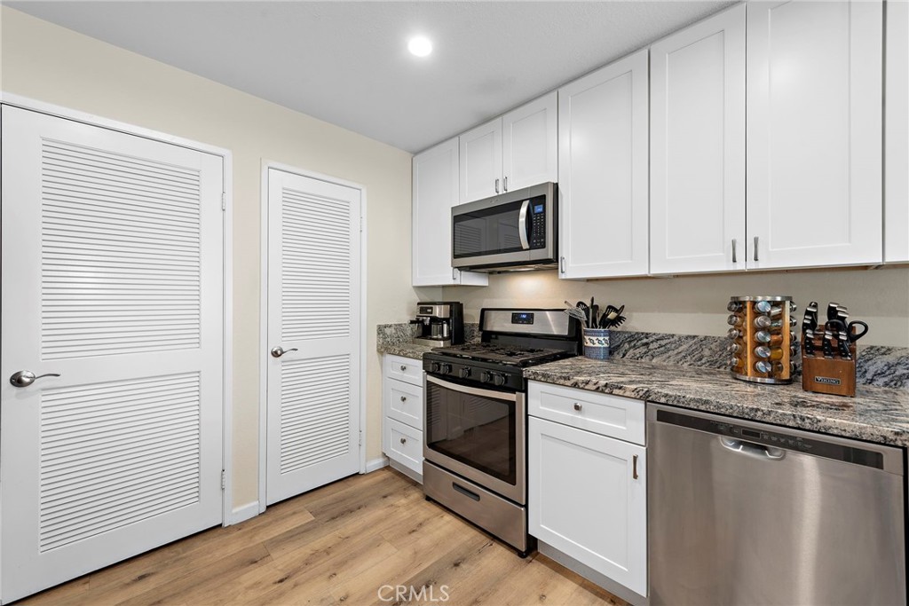 22 Exeter, Unit 23 Irvine, CA 92612 - Photo 13 of 30 a kitchen with stainless steel appliances granite countertop a stove a sink and a microwave