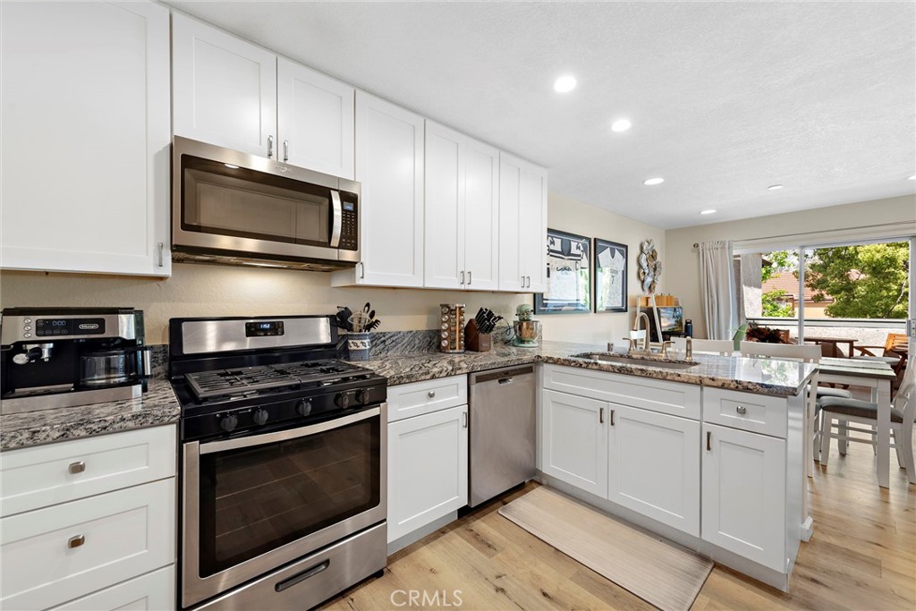 22 Exeter, Unit 23 Irvine, CA 92612 - Photo 14 of 30 a kitchen with stainless steel appliances granite countertop a stove microwave and sink