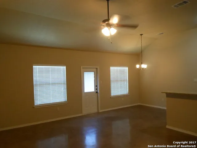 a view of an empty room with window and wooden floor