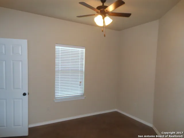an empty room with a window and a fan