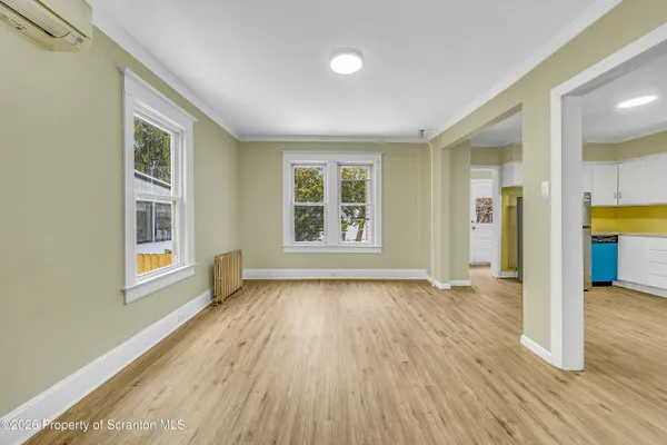 a view of an empty room with wooden floor and a window