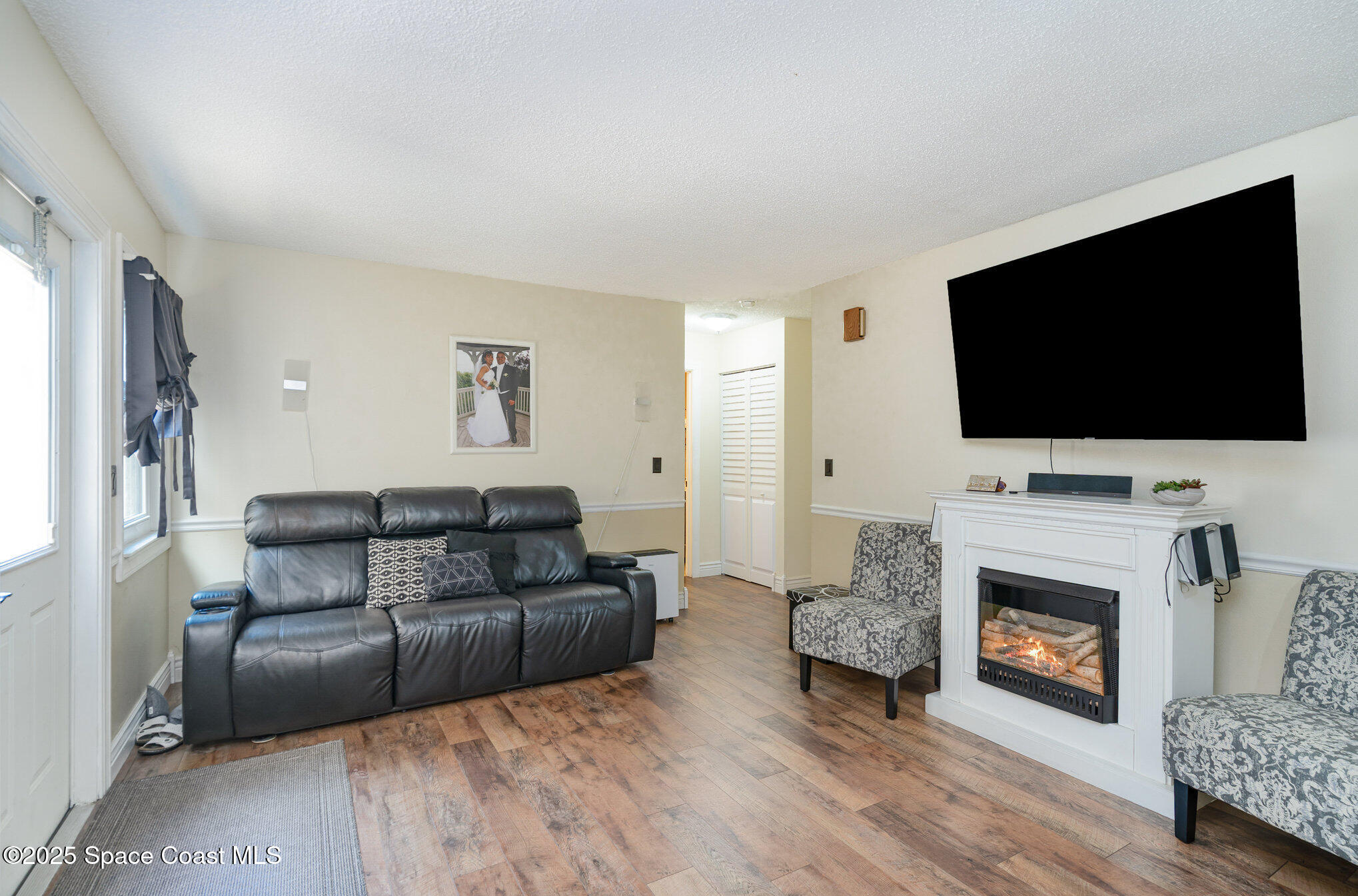 1010 Abada Court Northeast, Unit 102 Palm Bay, FL 32905 - Photo 11 of 37 a living room with furniture a flat screen tv and a fireplace