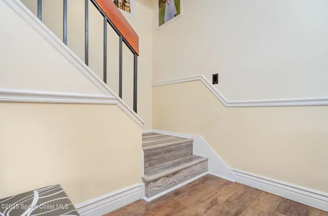 a view of staircase with wooden floor and white walls