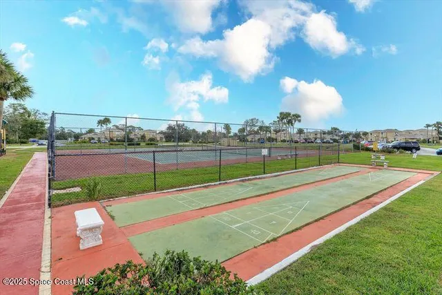 an aerial view of a tennis ground and a cars park side of the road