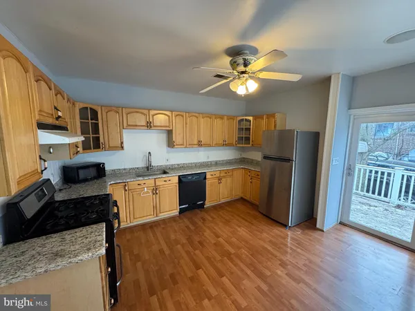 a kitchen with stainless steel appliances a refrigerator a sink dishwasher a stove with wooden cabinets and floor
