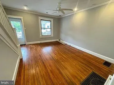 an empty room with wooden floor and windows