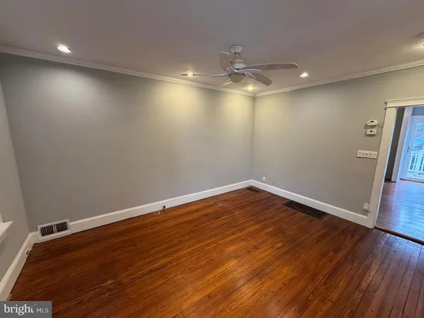 an empty room with wooden floor and fan