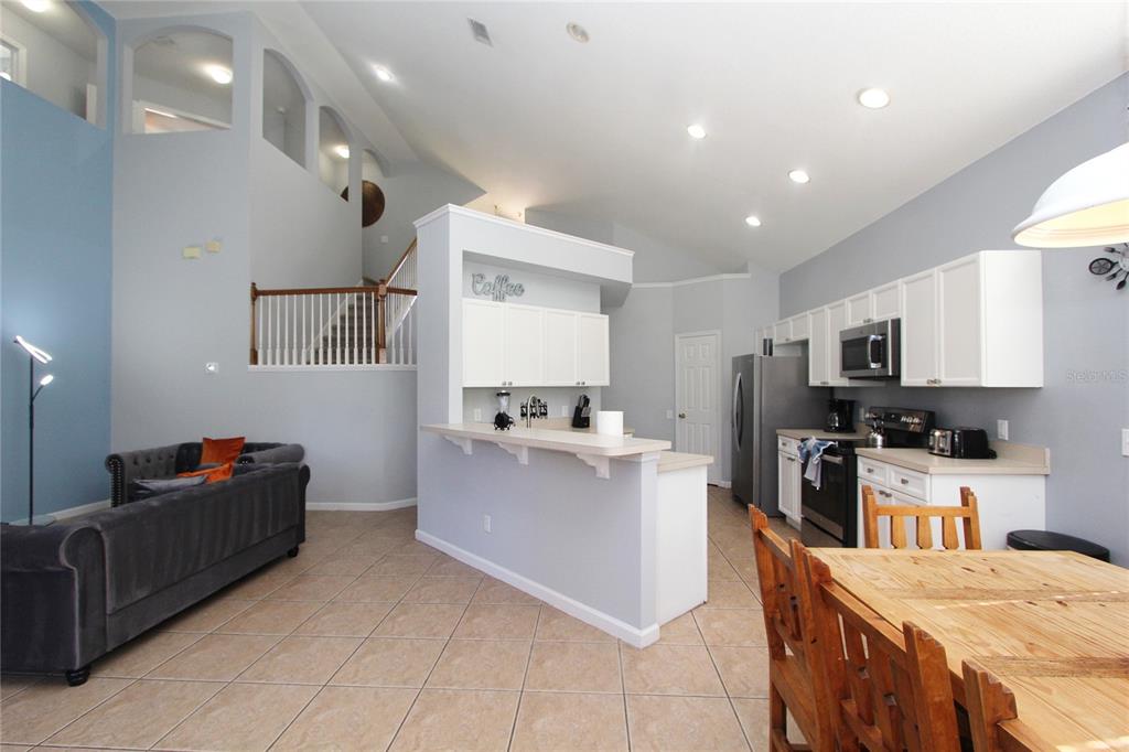8211 Fan Palm Way Kissimmee, FL 34747 - Photo 12 of 41 a kitchen with stainless steel appliances kitchen island granite countertop a refrigerator oven a sink dishwasher with a dining table and chairs