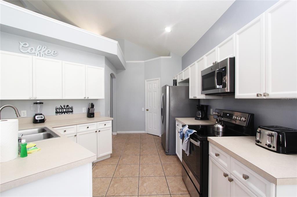 8211 Fan Palm Way Kissimmee, FL 34747 - Photo 7 of 41 a kitchen with a sink a stove top oven and white cabinets
