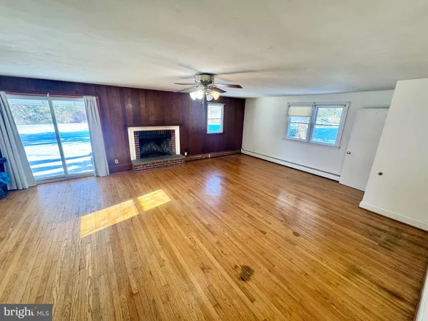 an empty room with wooden floor fireplace and windows