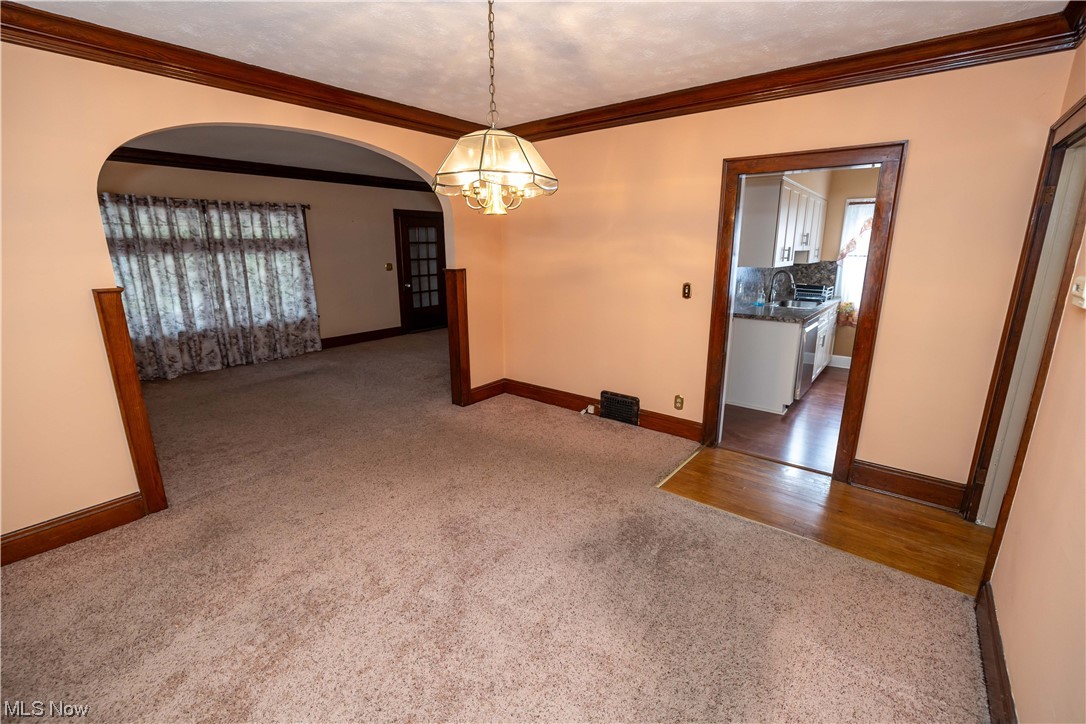 10105 Unity Avenue Cleveland, OH 44111 - Photo 7 of 35 Wood floored empty room featuring crown molding, sink, and an inviting chandelier