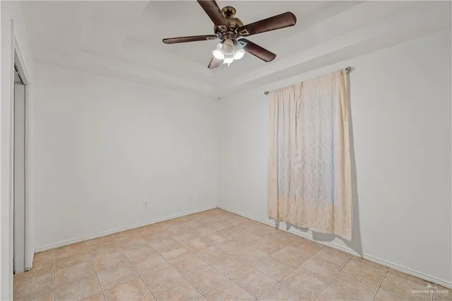 an empty room with a chandelier fan and windows