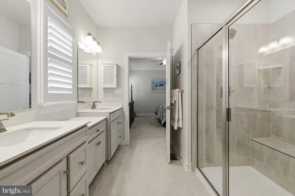 a spacious bathroom with a double vanity sink a mirror and a shower