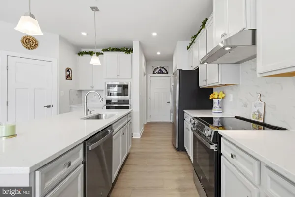 a kitchen with a sink a counter top space stainless steel appliances and cabinets