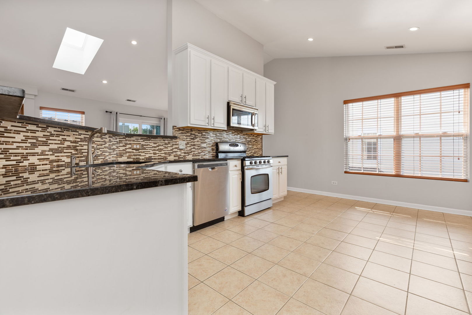 1981 West Cobblestone Road Romeoville, IL 60446 - Photo 9 of 27 a kitchen with stainless steel appliances granite countertop a stove a sink and a microwave