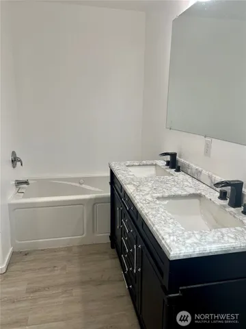 a bathroom with a granite countertop sink and a bathtub