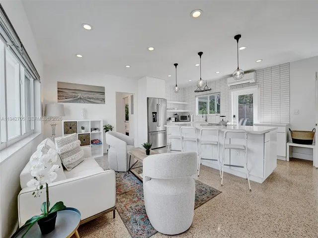 a living room with furniture a dining table wooden floor and kitchen view
