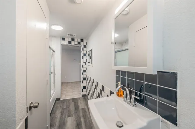 a bathroom with a sink and mirror with shower