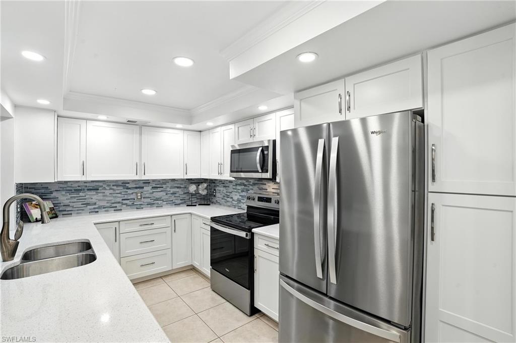 3380 Timberwood Circle Naples, FL 34105 - Photo 5 of 38 a kitchen with a refrigerator sink and stainless steel appliances