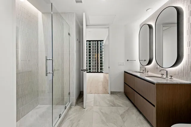 a bathroom with a double vanity sink mirror and shower