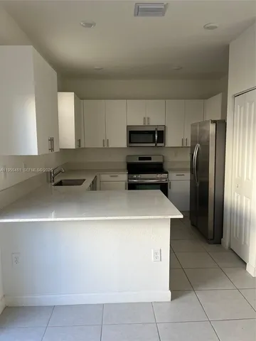 a kitchen with a sink a refrigerator and cabinets