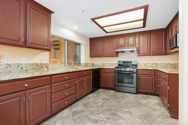a kitchen with granite countertop a stove top oven sink and cabinets