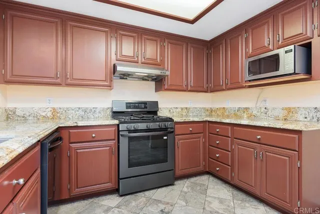 a kitchen with granite countertop cabinets stainless steel appliances and a sink