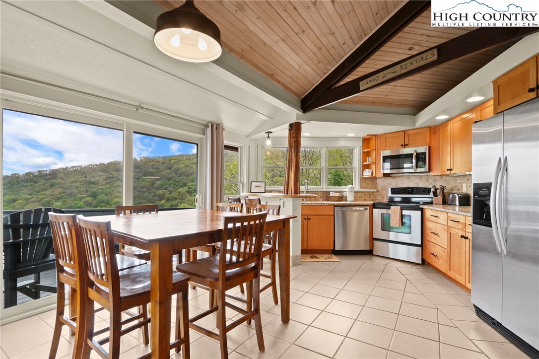 104 Longview Court Seven Devils, NC 28604 - Photo 11 of 46 a kitchen with stainless steel appliances granite countertop a stove top oven a sink dishwasher a dining table and chairs with wooden floor
