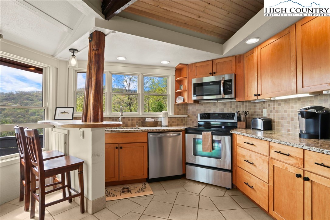 104 Longview Court Seven Devils, NC 28604 - Photo 12 of 46 a kitchen with stainless steel appliances granite countertop a stove top oven a sink dishwasher a dining table and chairs with wooden floor