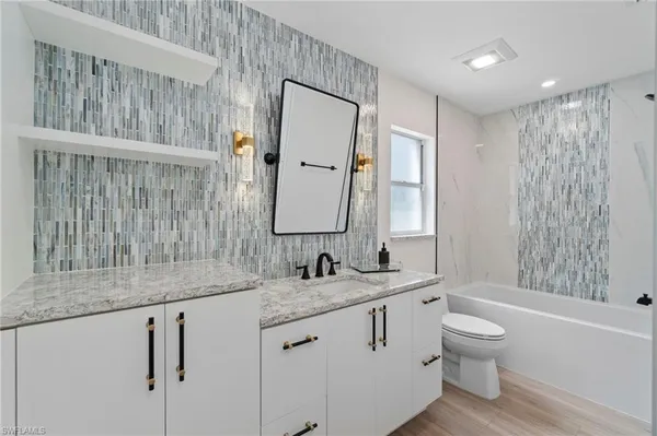 a bathroom with a granite countertop sink toilet and shower