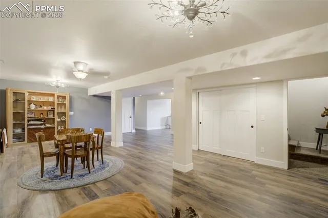 a dining room with wooden floor a chandelier a glass table and chairs