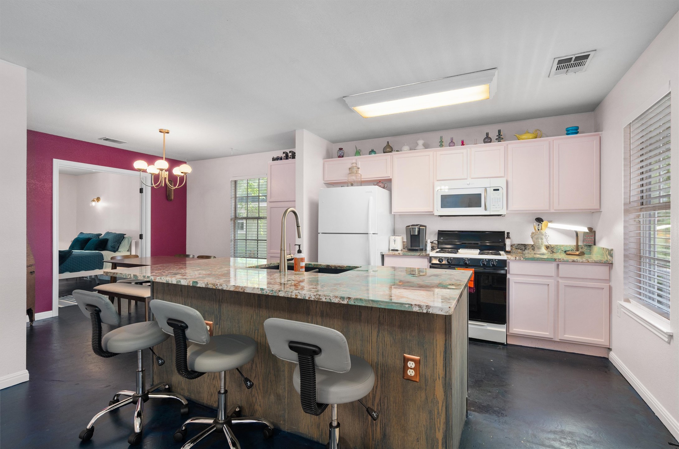 1407 Sanchez Street Austin, TX 78702 - Photo 9 of 34 Kitchen with a breakfast bar area, white appliances, light stone counters, a center island with sink, and hanging lights