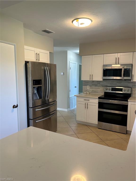 1446 Mandel Road Fort Myers, FL 33919 - Photo 2 of 22 a kitchen with kitchen island a refrigerator and a stove top oven