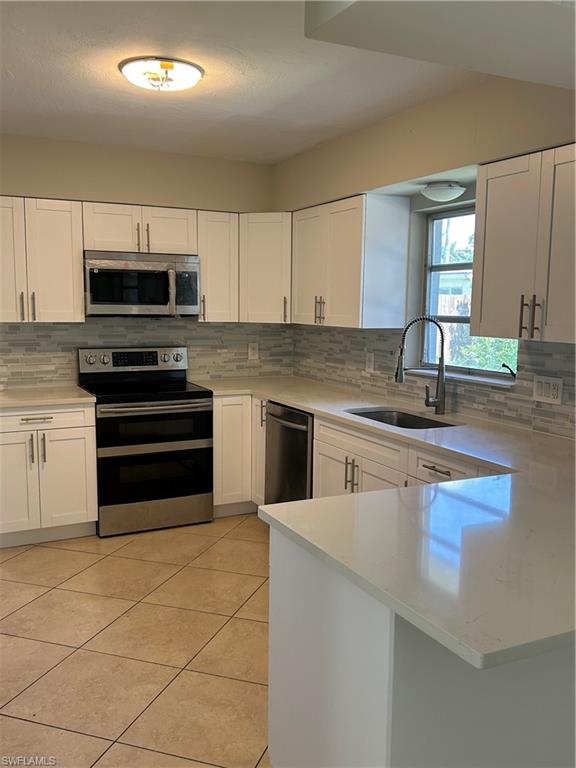1446 Mandel Road Fort Myers, FL 33919 - Photo 3 of 22 a kitchen with stainless steel appliances a stove sink microwave and cabinets