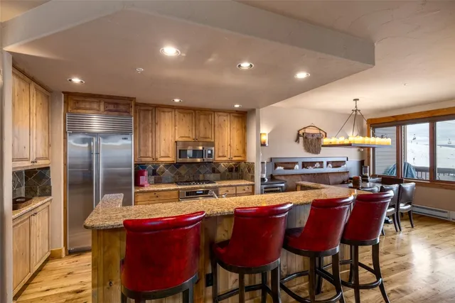 a kitchen with stainless steel appliances a dining table chairs stove and refrigerator